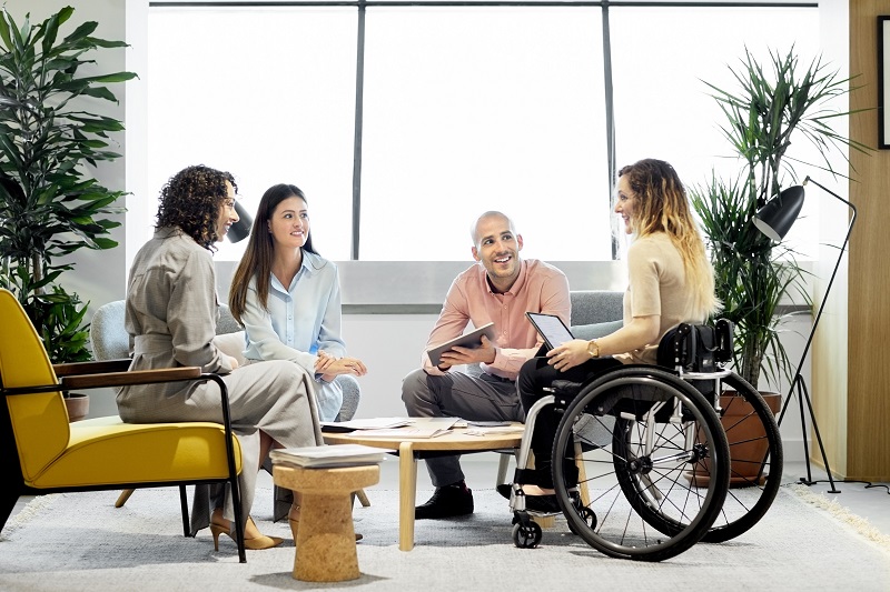 Disabled businesswoman discussing with colleagues. Male and female professionals planning in business meeting. They are sitting at office.